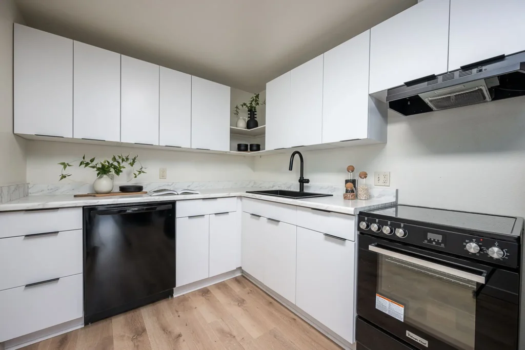Modernized apartment kitchen in Bend, Oregon featuring new cabinetry, updated countertops, black fixtures, and upgraded appliances following renovation.