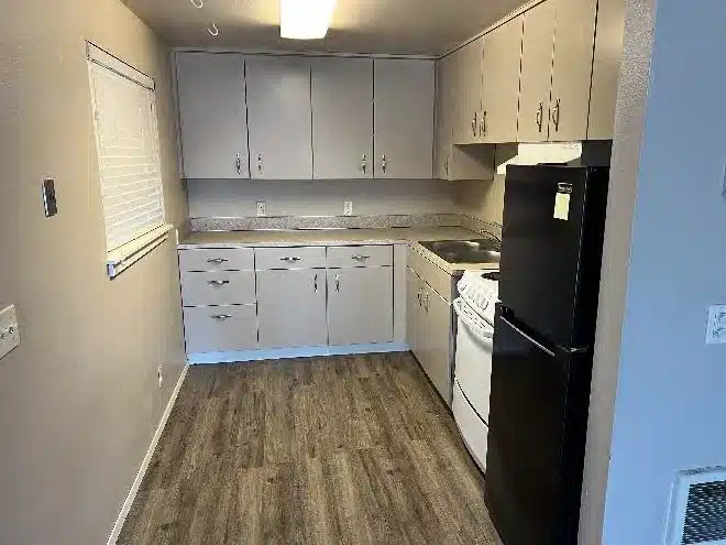 Original apartment kitchen before renovation showing older cabinets, appliances, and finishes in a Bend, Oregon multifamily property.